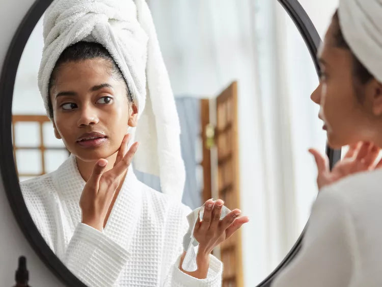 Woman with a towel wrapped around her hair performing her nighttime skincare routine