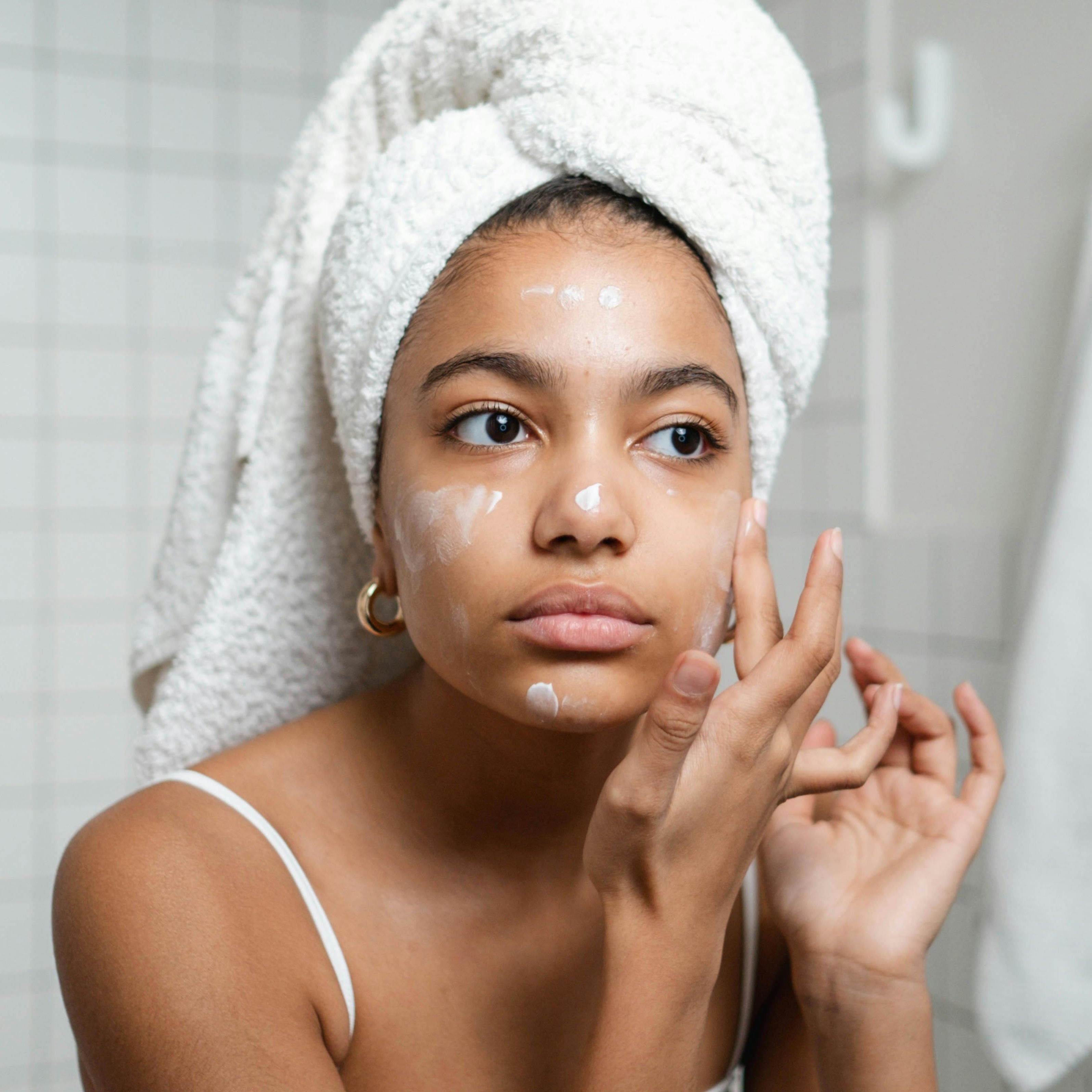 Teen applying skin care cream on face