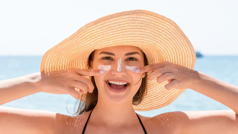 Woman applying tinted sunscreen outdoors, showing natural sun protection and even skin tone