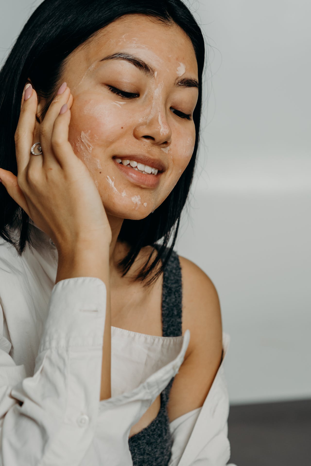 woman in a white shirt applying cream to her face