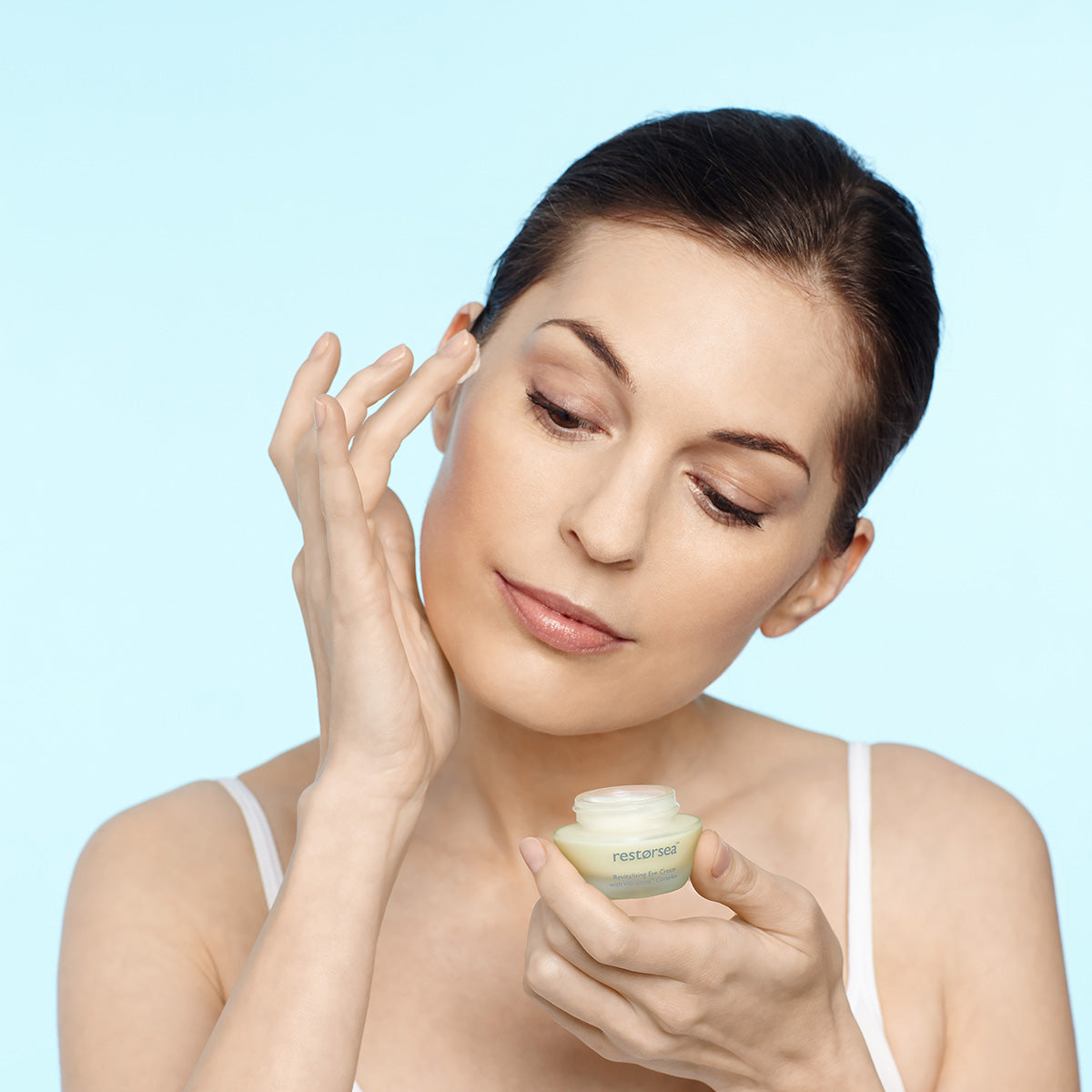 Model with bent head applying Restorsea Revitalizing Eye Cream with Vibransea Complex, Front view